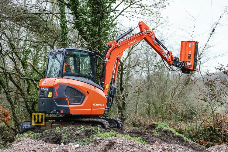 Minikoparka gąsienicowa Kubota KX042-5 widoczna z boku która przycina korony drzew